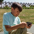 Tense boy play video game on smartphone outdoors