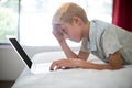 Tense boy using laptop on bed in bedroom Royalty Free Stock Photo