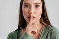 Tense caucasian girl showing silence gesture at camera