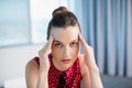 Tense female business executive sitting with hand on forehead