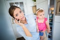 Tensed woman talking on mobile phone while carrying baby girl Royalty Free Stock Photo