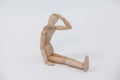 Tensed wooden figurine sitting with hand on head