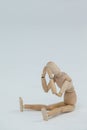 Tensed wooden figurine sitting with hands on head