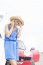 Tensed young woman using cell phone by broken down cars