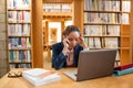 Tensed young woman using laptop in library