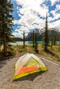 Tent on alpine lake shoreline surrounded by mountains Royalty Free Stock Photo