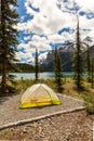 Tent on alpine lake shoreline surrounded by mountains Royalty Free Stock Photo