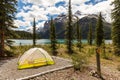 Tent on alpine lake shoreline surrounded by mountains Royalty Free Stock Photo