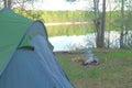 Tent, campfire on bank of lake in forest in beautiful nature place at Summer.