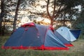 Tent on a glade in the forest in the rays of sunset