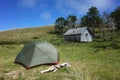 Tent on green grass by old wooden house and small forest on hill, Summer vacation beautiful peaceful scenery, Camping Royalty Free Stock Photo