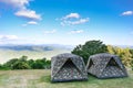 Tent on the hill beneath the mountains under clear sky in beautiful summer landscape camp. The camouflage tent is on green fields Royalty Free Stock Photo