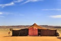 A tent made of camel skin in desert with mountains on background