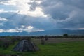 Tent with mountains silhouettes and cloudy sky with sunrays shining through them. Royalty Free Stock Photo