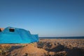 Tent, summer camping on the beach, against the backdrop of the sea and sky. A bright blue large tent stands on the sandy