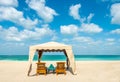 Tent with two sun beds, a table and towels on a sandy beach