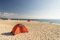 Tents on beach of white sandunder blue sky