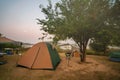 Tents and chairs under the trees in the morning, the moon in the sky at the camping ground Royalty Free Stock Photo