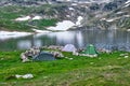 Tents pitched near glacial lake Bucura, at high altitude, with stone piles around them for wind protection - Retezat mountains. Royalty Free Stock Photo