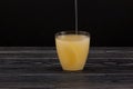 Tepache - Popular mexican fermented pineapple drink. Chilled drink poured into glass. Dark background, copy space