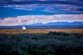 Tepee in open field with mountains in the background