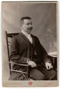 Vintage photo shows man with moustache sits on a chair