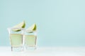 Tequila cocktails with fresh piece lime, rim of salt in shot glass on white wood table and blue color wall, copy space. Royalty Free Stock Photo