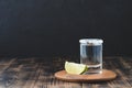 Tequila shot and lime slice on wooden table/Tequila shot and lime slice on wooden table with copy copyspace on dark background Royalty Free Stock Photo