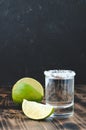 Tequila shot and lime slice on wooden table/Tequila shot and lime slice on wooden table. Dark background Royalty Free Stock Photo