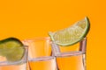 Tequila shot with a slice of lime on the glass orange background Royalty Free Stock Photo