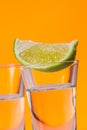 Tequila shot with a slice of lime on the glass orange background Royalty Free Stock Photo