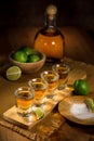 Tequila shots grouped together with a bottle and cut limes on a restaurant bar table