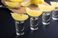 Tequila shots with lemon slices and pieces in the background.