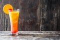 Tequila sunrise cocktail in glass on wooden table.