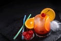 Tequila Sunrise cocktail, orange, ice cube, maraschino cherries, straws on a wet black slate tray with copy space. Royalty Free Stock Photo