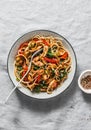 Teriyaki chicken, bell peppers, onions, spinach and rice noodles stir fry on grey background, top view. Asian style Royalty Free Stock Photo