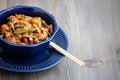 Teriyaki chicken with noodles and vegetables stir-fry in a bowl, wooden background. Udon noodles, teriyaki chicken, vegetables,