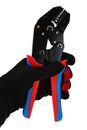 Terminal crimping press pliers with closed jaws, held in left hand in thin black nylon/polyester/spandex glove