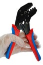 Terminal crimping press pliers, half opened jaws, held in left hand in transparent glove used in electrotechnical installations