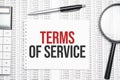 Terms of Service text on paper with calculator,magnifier ,pen on the graph background Royalty Free Stock Photo