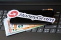 TERNOPIL, UKRAINE - SEPTEMBER 6, 2022 MoneyGram paper logotype lies on black laptop with euro bills. Moneygram is American cross