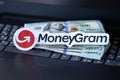 TERNOPIL, UKRAINE - SEPTEMBER 6, 2022 MoneyGram paper logotype lies on black laptop with US dollar bills. Moneygram is American