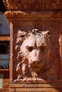 Terra cotta lion face medallion in red brick column in sun Royalty Free Stock Photo