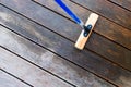 Terrace cleaning. Renovating a gray terrace using a hard scrub brush and green gel for renovating faded, gray boards