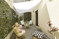 Terrace with fabric and wood hammocks, wicker furniture with fabric seats, decorative plants, white fabric awnings, stone floors