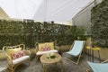 Terrace with fabric and wood hammocks, wicker furniture with fabric seats, decorative plants, white fabric awnings, stone floors,