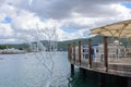 Terrace of a fish restaurant on the water. Umbrellas, wooden chairs and tables against the backdrop of the sea and mountains. Royalty Free Stock Photo