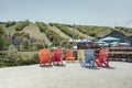 Terrace with folding beach chairs with a view of a lake, houses and a hill with green trees