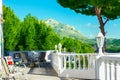 Terrace by the pool of luxurious white villa with chairs table fascinating view of valley mountains covered with green trees