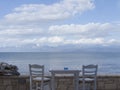 Terrace view with a gray table and two gray chairs, sea, clouds